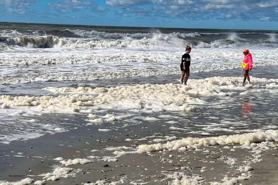 People wade through PFAS-contaminated sea foam at North Carolina’s Holden Beach in October 2022. Credit: Clean Cape Fear