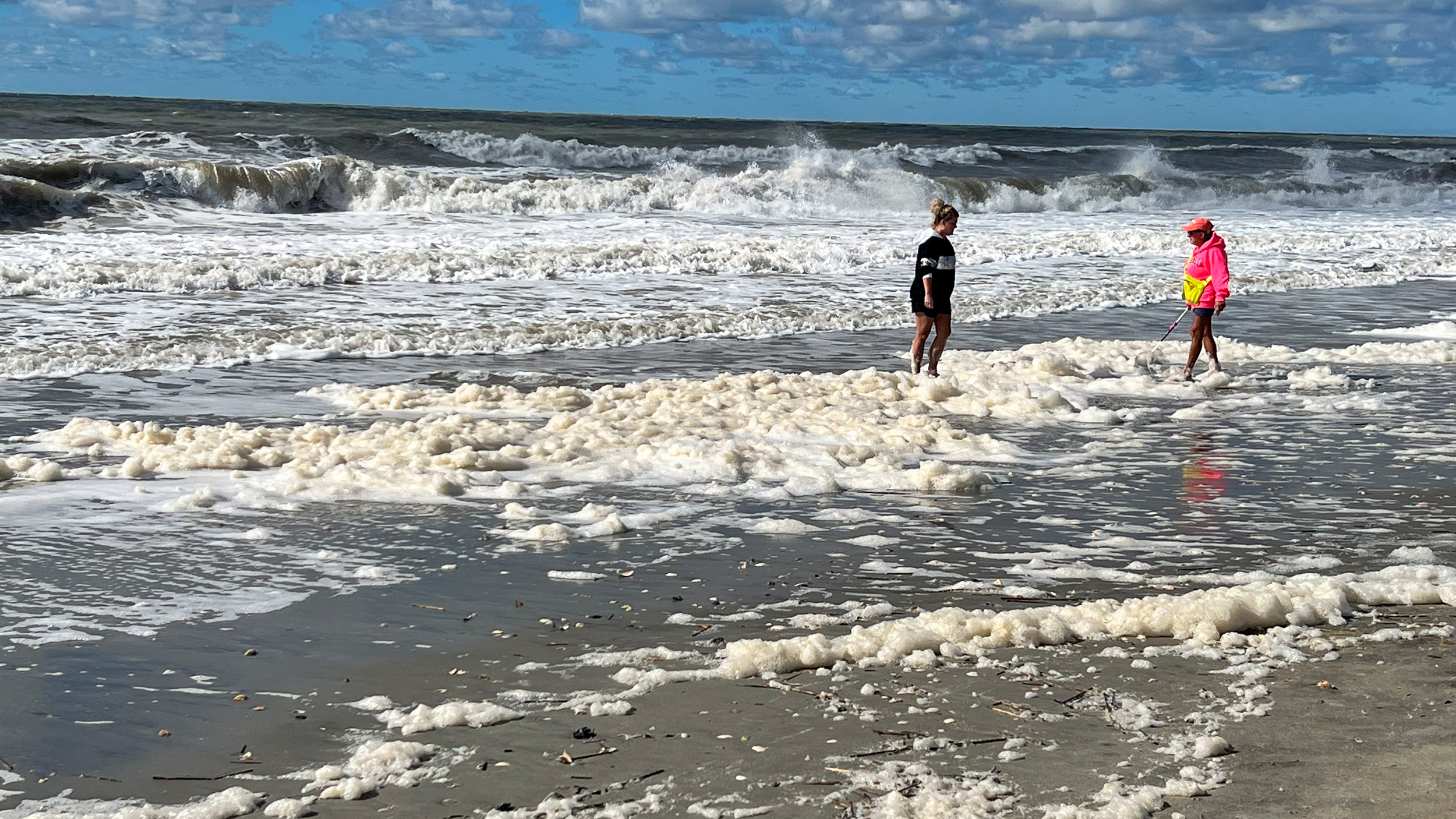 People wade through PFAS-contaminated sea foam at North Carolina’s Holden Beach in October 2022. Credit: Clean Cape Fear