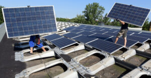 Workers remove solar panels from an industrial building. Credit: Waltraud Grubitzsch/picture alliance via Getty Images