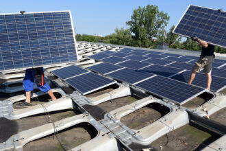 Workers remove solar panels from an industrial building. Credit: Waltraud Grubitzsch/picture alliance via Getty Images
