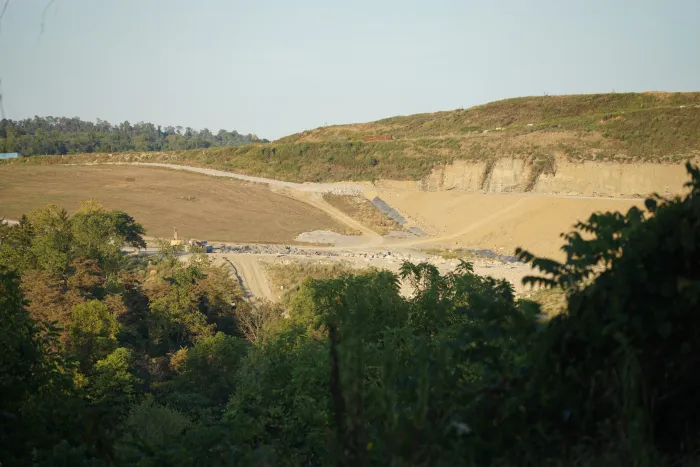 Image shows a landscape view of the landfill, a mix of sandy and brown colors with foliage at the edges