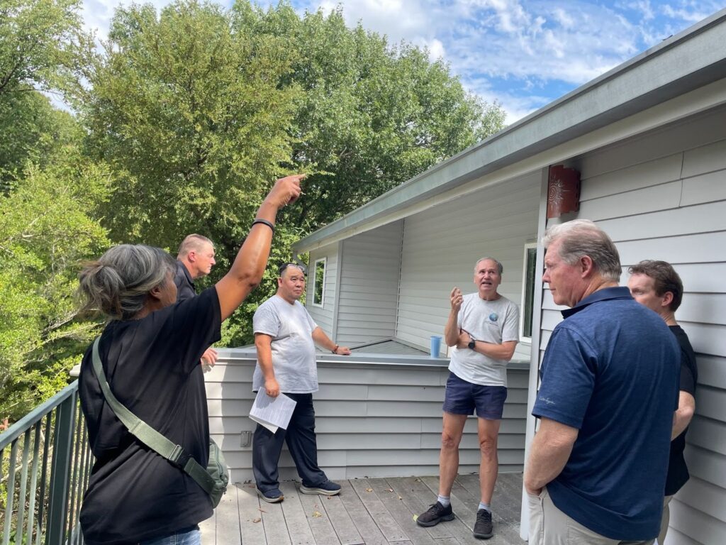 Paul Westbrook answers questions from a tour group about the cost savings and resistance of the metal roof he got installed nearly 30 years ago. Credit: Arcelia Martin/Inside Climate News