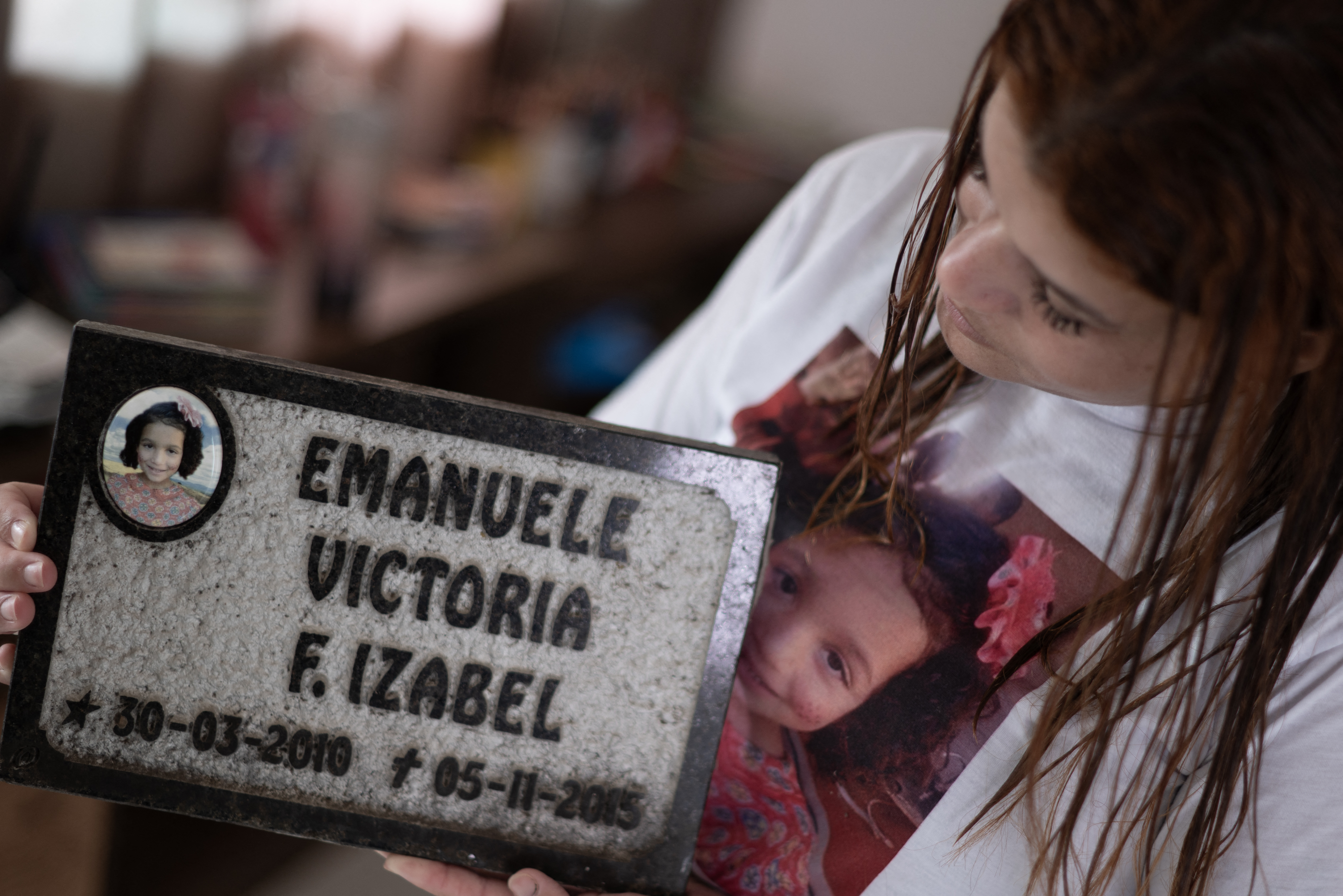 Pamela Rayane Fernandes holding a tombstone of her 5-year-old daughter Emanuelle, who died in Bento Rodriguez, Brazil, following the collapse of the Fundão mine dam in the mountains of southeast Brazil nine years ago. Credit: Douglas Magno/AFP via Getty Images