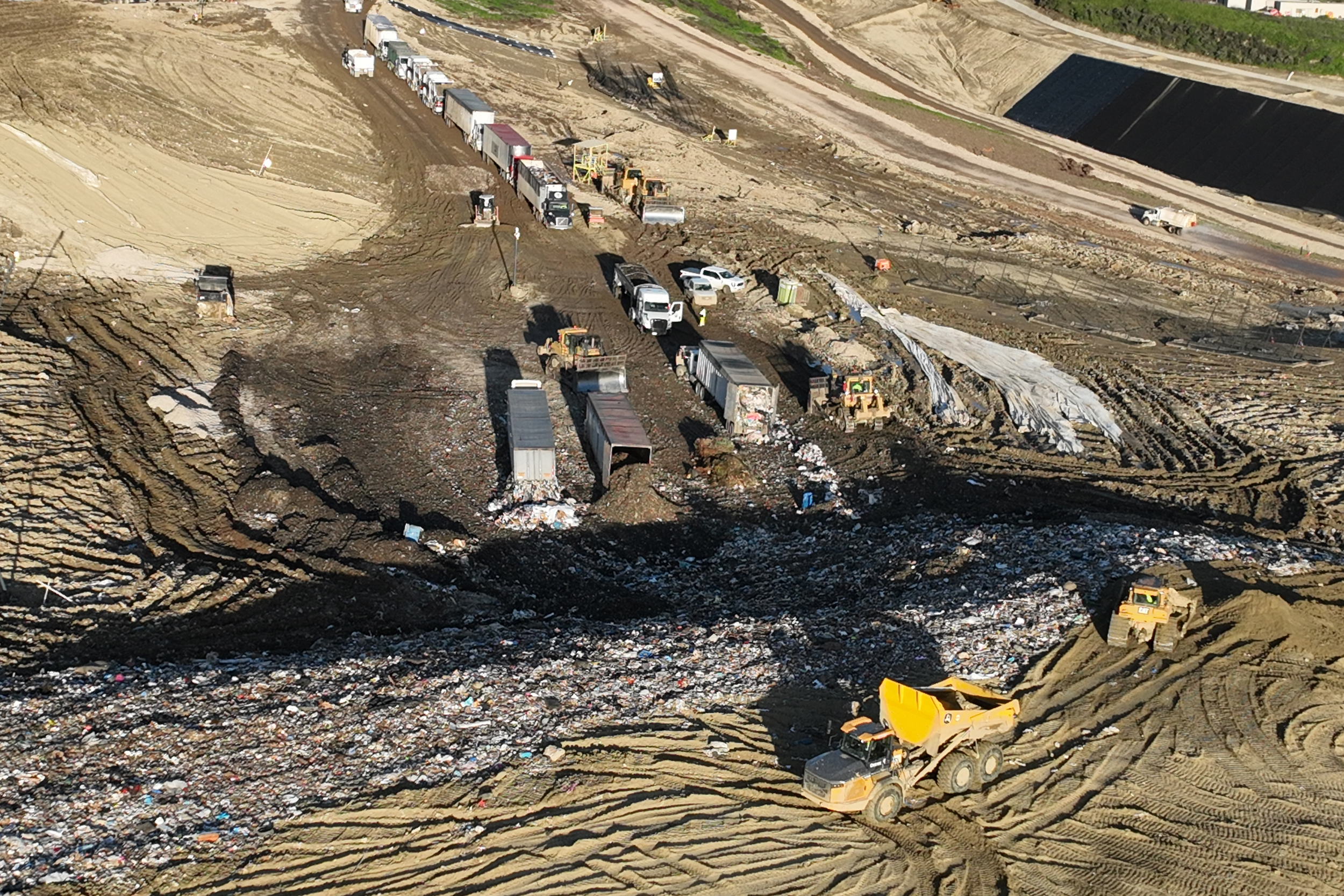 An aerial view of trucks unloading and spreading trash over a hill at the Chiquita Canyon Landfill in Castaic, Calif., in February 2024. Credit: Allen J. Schaben/Los Angeles Times via Getty Images