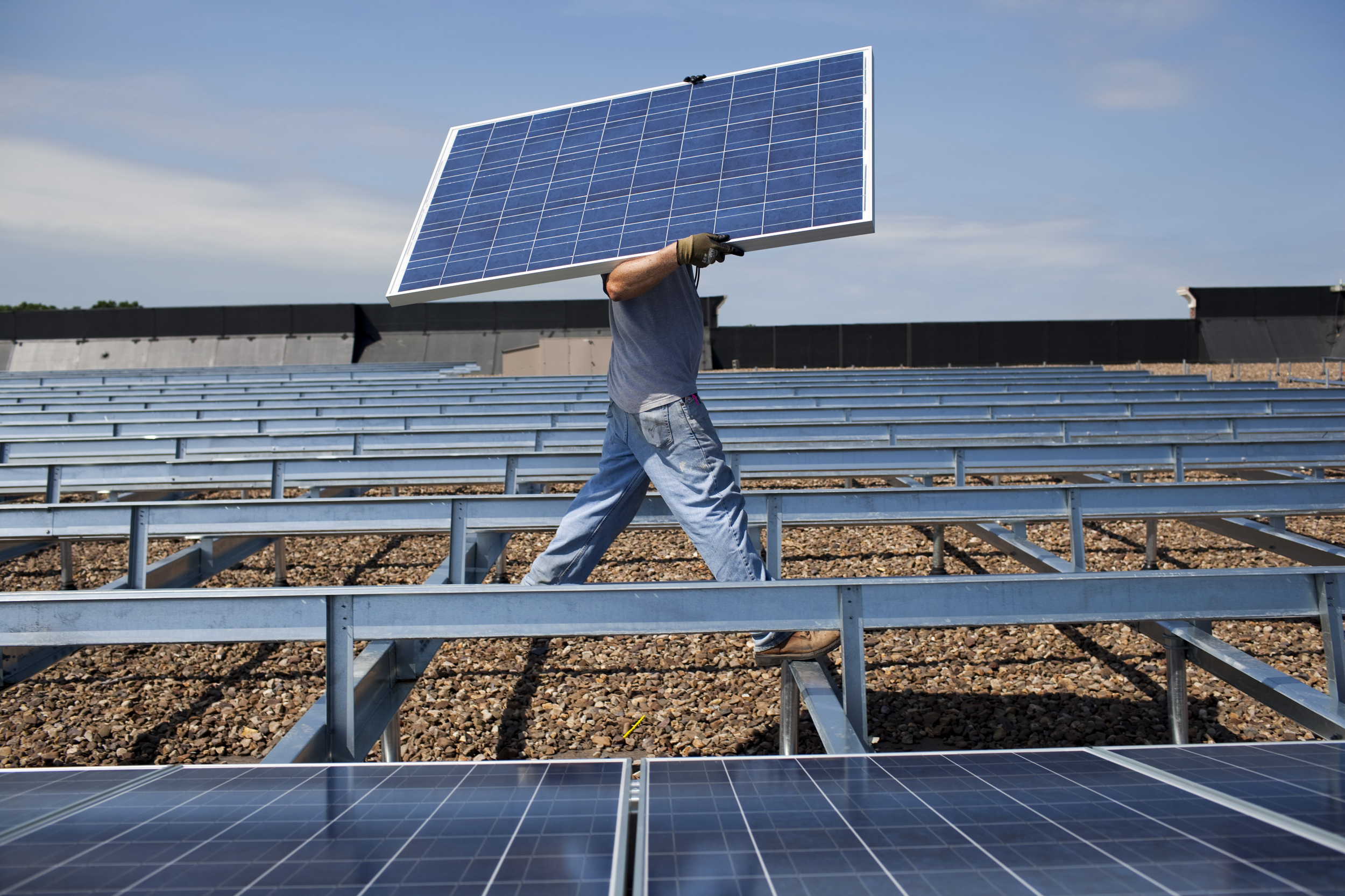 Contractors install solar panels on a roof in Hamilton Township, N.J. Credit: Robert Nickelsberg/Getty Images