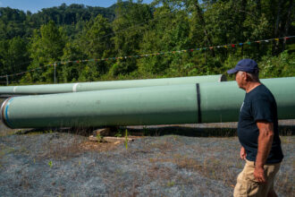Local resident Bobby Amerson walks past sections of steel pipe to be used for the Mountain Valley Pipeline in Callaway, Va., on Aug. 30, 2022. Credit: Robert Nickelsberg/Getty Images