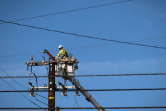 A Pacific Gas and Electric worker replaces power poles destroyed during the Eaton Fire in Altadena, Calif., on Jan. 22. Credit: Sarah Reingewirtz/MediaNews Group/Los Angeles Daily News via Getty Images