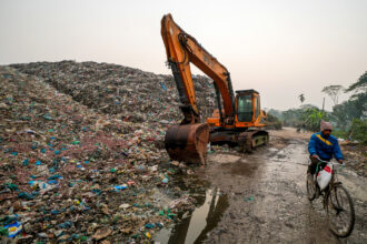 A cyclist passes a landfill, a known emitter of Methane, on Jan. 21 in Barisal, Bangladesh. Credit: Niamul Rifat/Anadolu via Getty Images