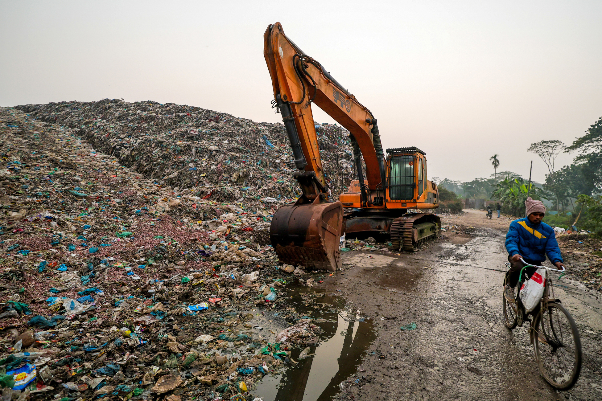 A cyclist passes a landfill, a known emitter of Methane, on Jan. 21 in Barisal, Bangladesh. Credit: Niamul Rifat/Anadolu via Getty Images
