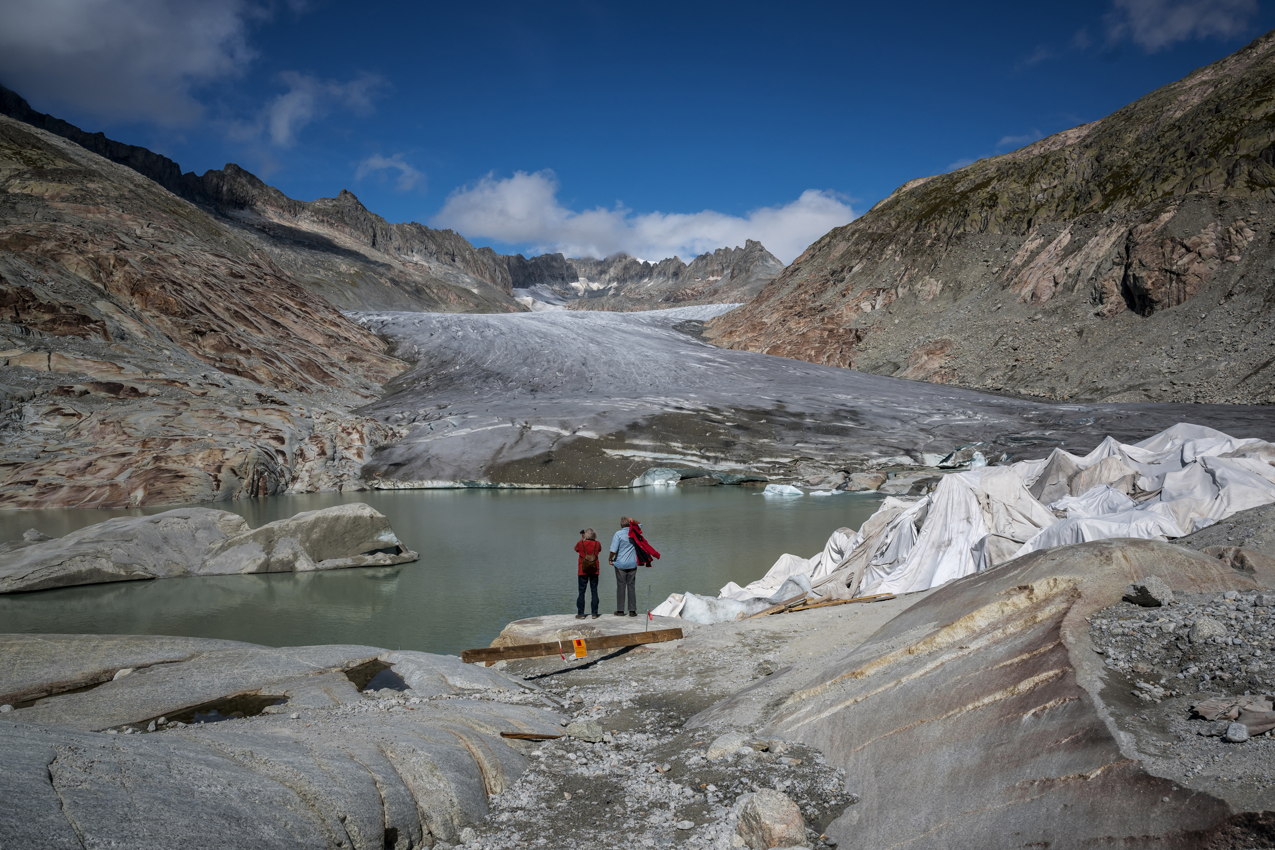 People observe the Rhone Glacier as it melts into its glacial lake in the Swiss Alps. Credit: Fabrice Coffrini/AFP via Getty Images