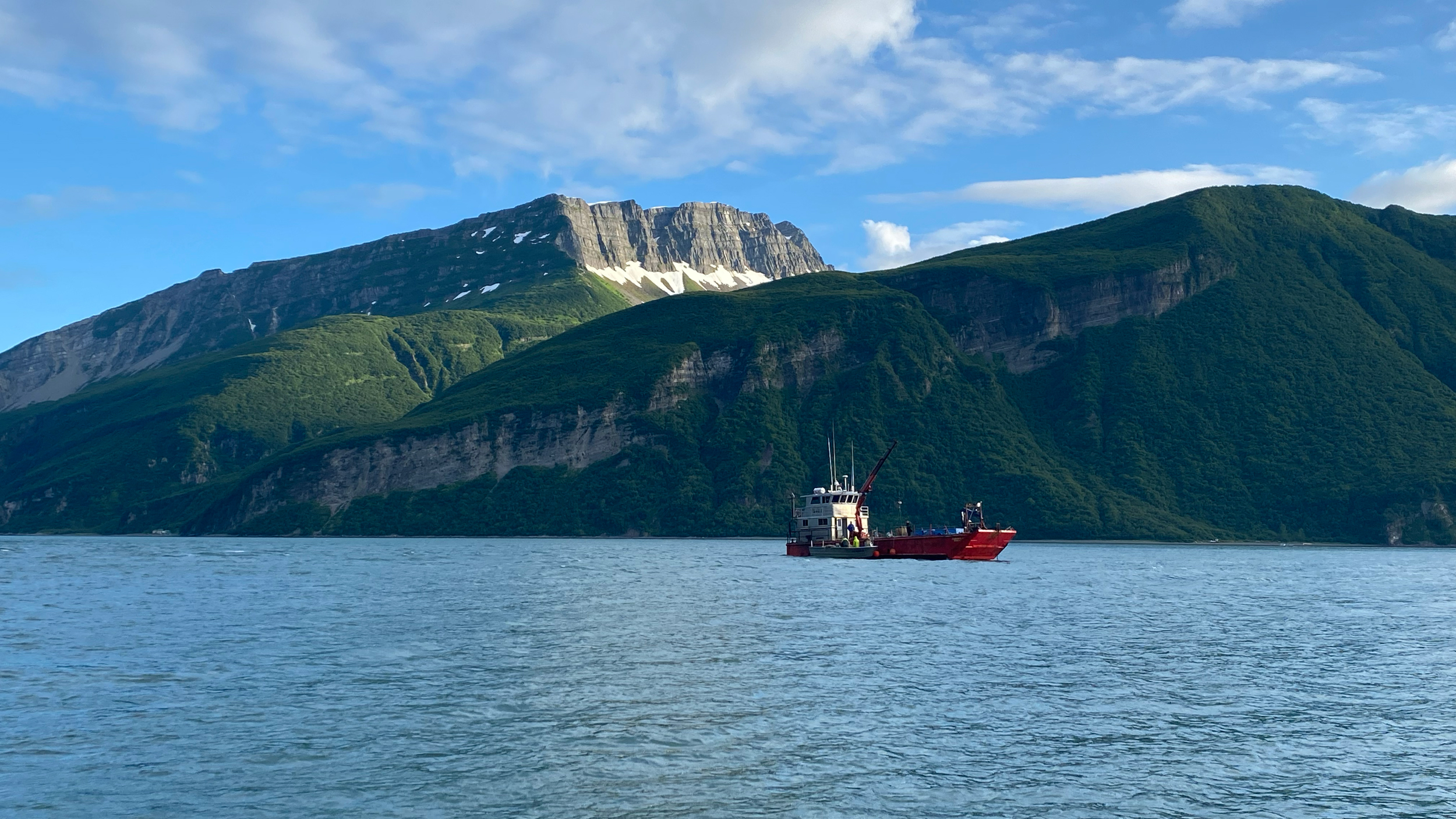 A fishing tender anchored in Tuxedni Channel, with Lake Clark National Park in the background. The tender buys salmon from the bay’s fishermen and transports it across the inlet to a processing plant in the town of Kenai. Credit: Max Graham/Northern Journal