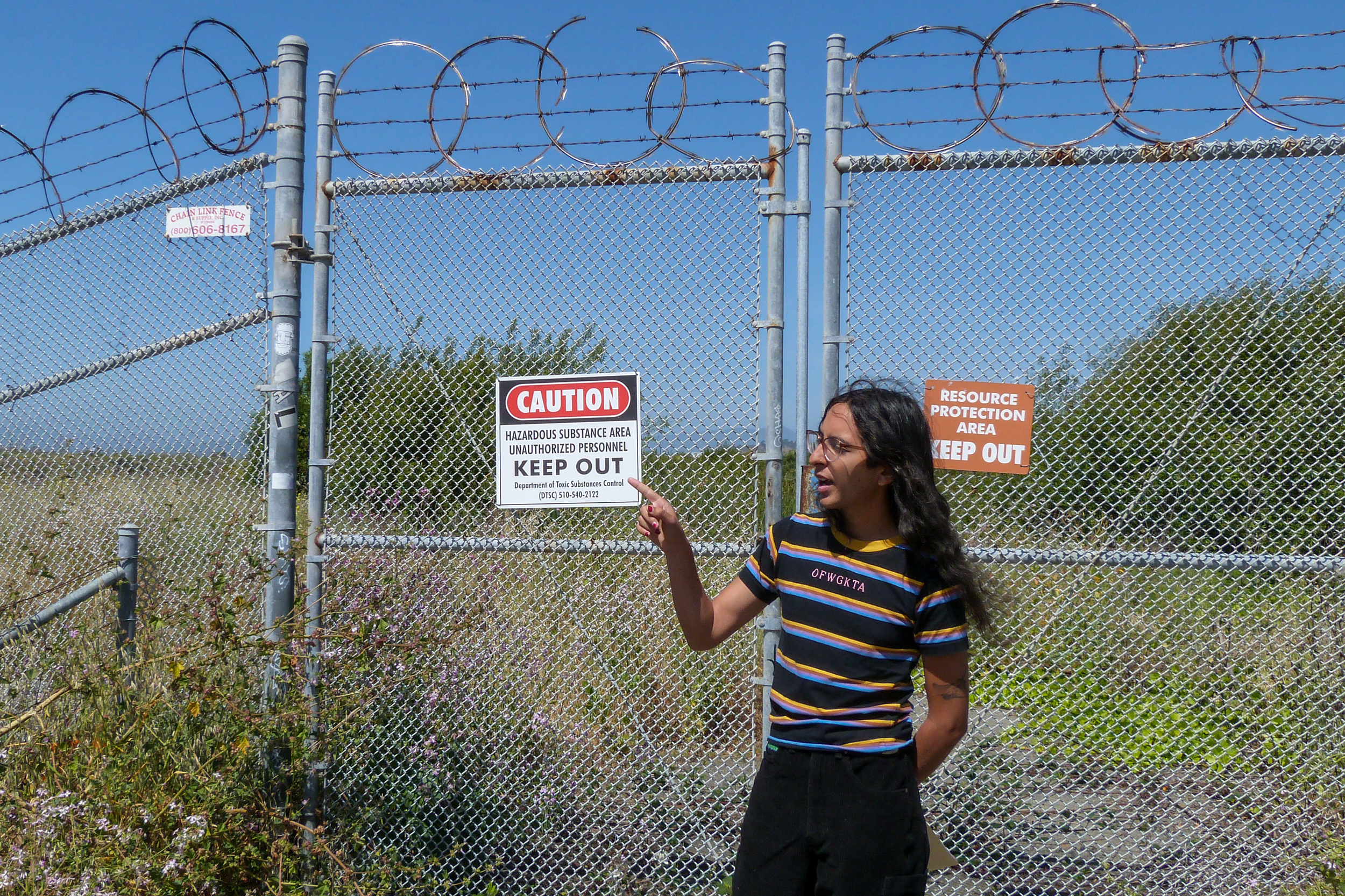 Luna Angulo, born and raised in Richmond, Calif., stands in front of a site where long-defunct chemical plants dumped toxic wastes, near another hazardous site likely to flood as sea level rises along the city’s shoreline. Credit: Liza Gross/Inside Climate News