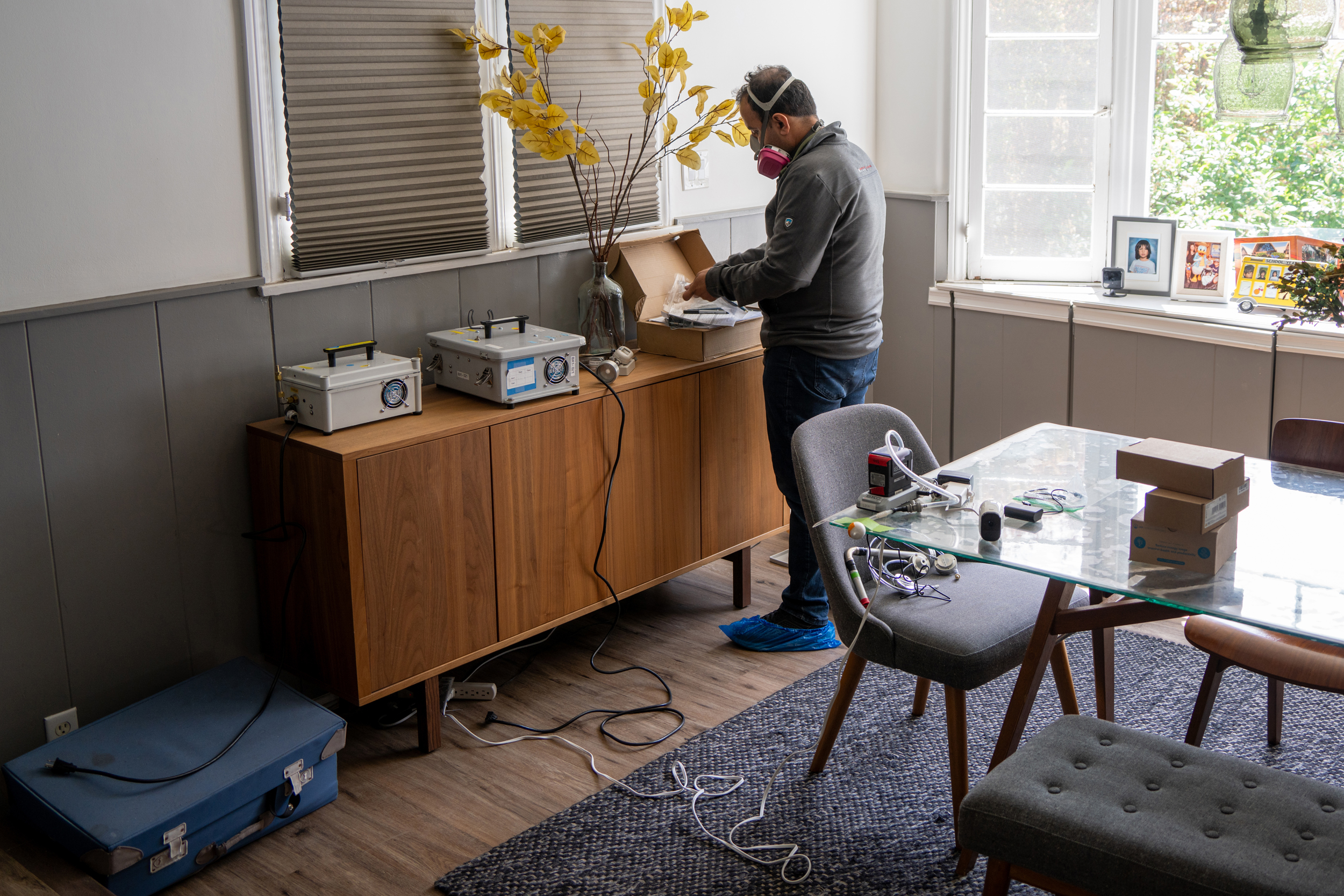 Parham Azimi, a Harvard University researcher, sets up monitoring equipment in the dining room of the Valdez-Perera home on April 1.