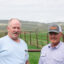 Tim Teichert and Jason Thornock, third-generation ranchers in Cokeville, Wyo., stand in Teichert’s backyard, where Thornock’s property and Rocky Mountain Power transmission lines are seen in the distance.
