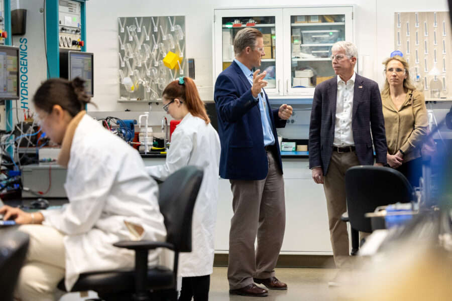 Chris Wright is inside a lab, talking to people standing near scientists in lab coats.