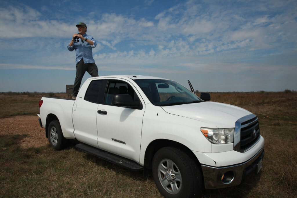 James Dodson, founder of the San Antonio Bay Partnership, stands in his truck bed near a water pond for wildlife he built on the private Welder Ranch in Calhoun County in February 2025. Credit: Dylan Baddour / Inside Climate News