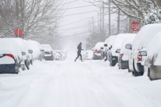 A jogger makes their way across a snowy street after a winter storm hit Seattle on Feb. 13, 2021. Credit: David Ryder/Getty Images