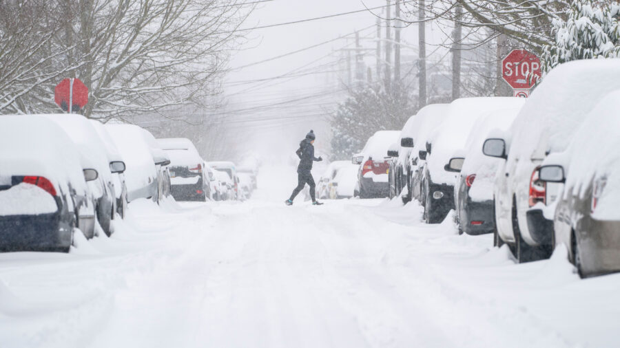 A jogger makes their way across a snowy street after a winter storm hit Seattle on Feb. 13, 2021. Credit: David Ryder/Getty Images