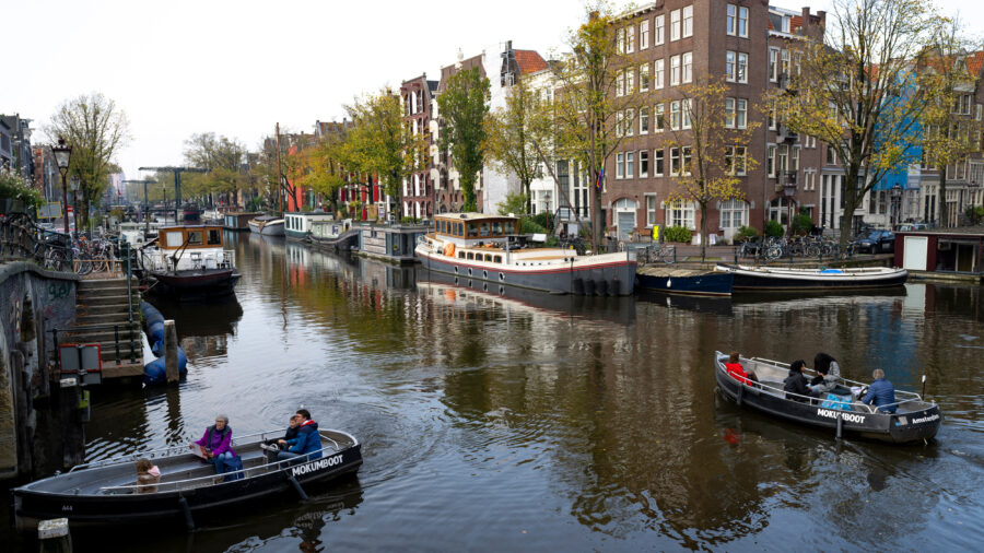 People navigate small boats through the Lekkersluis canal in Amsterdam. Credit: Nick Gammon/AFP via Getty Images