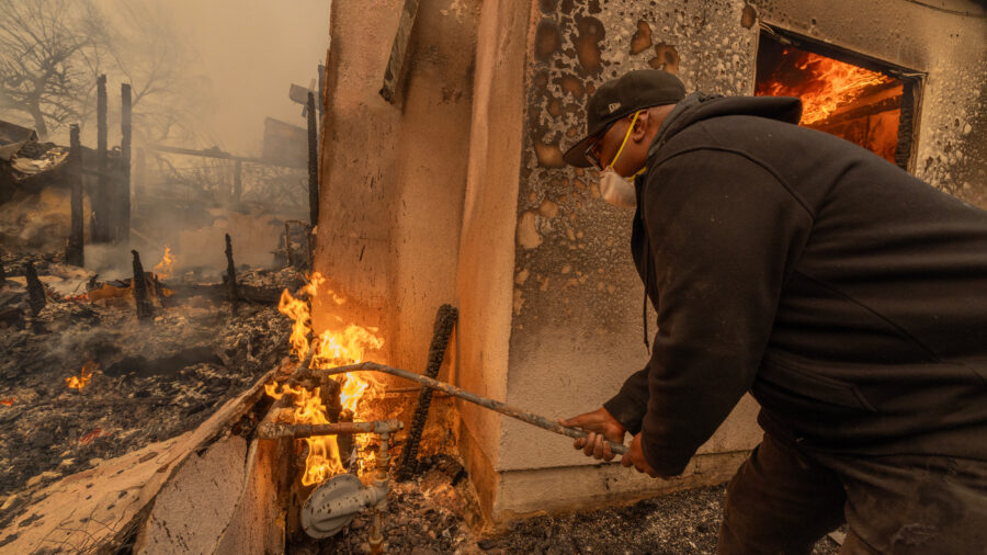 A man uses a wrench stuck into a pipe to turn off a burning gas line during the Eaton Fire on Jan. 8 in Altadena, Calif. Credit: David McNew/Getty Images
