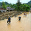 People wade through floodwater in the aftermath of flash floods on Dec. 2 in Central Tapanuli, North Sumatra. Credit: Yt Hariono/AFP via Getty Images