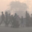 People walk across a road amid dense smog in Lahore on Dec. 12. Credit: Arif Ali/AFP via Getty Images