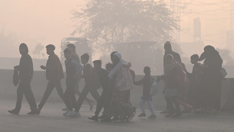 People walk across a road amid dense smog in Lahore on Dec. 12. Credit: Arif Ali/AFP via Getty Images