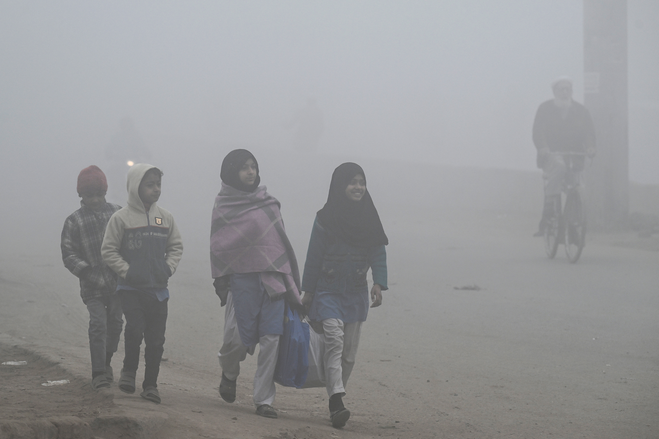 Children walk to school amid dense smog in Lahore on Dec. 16. Credit: Arif Ali/AFP via Getty Images