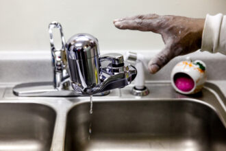 Fred the handyman at the Shiloh Commons installs a new water filter in a residence January 21, 2016 in Flint, Michigan. The city's water supply had been contaminated by lead after a switch from Lake Huron to the Flint river as a source in April 2014. Credit: Sarah Rice/Getty Images