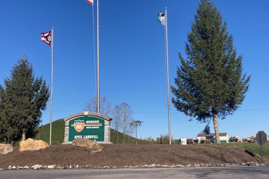 Image shows the Apex landfill exterior sign with flags above it