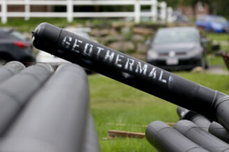 A pipe marked "geothermal" leans on other pipes in a residential neighborhood