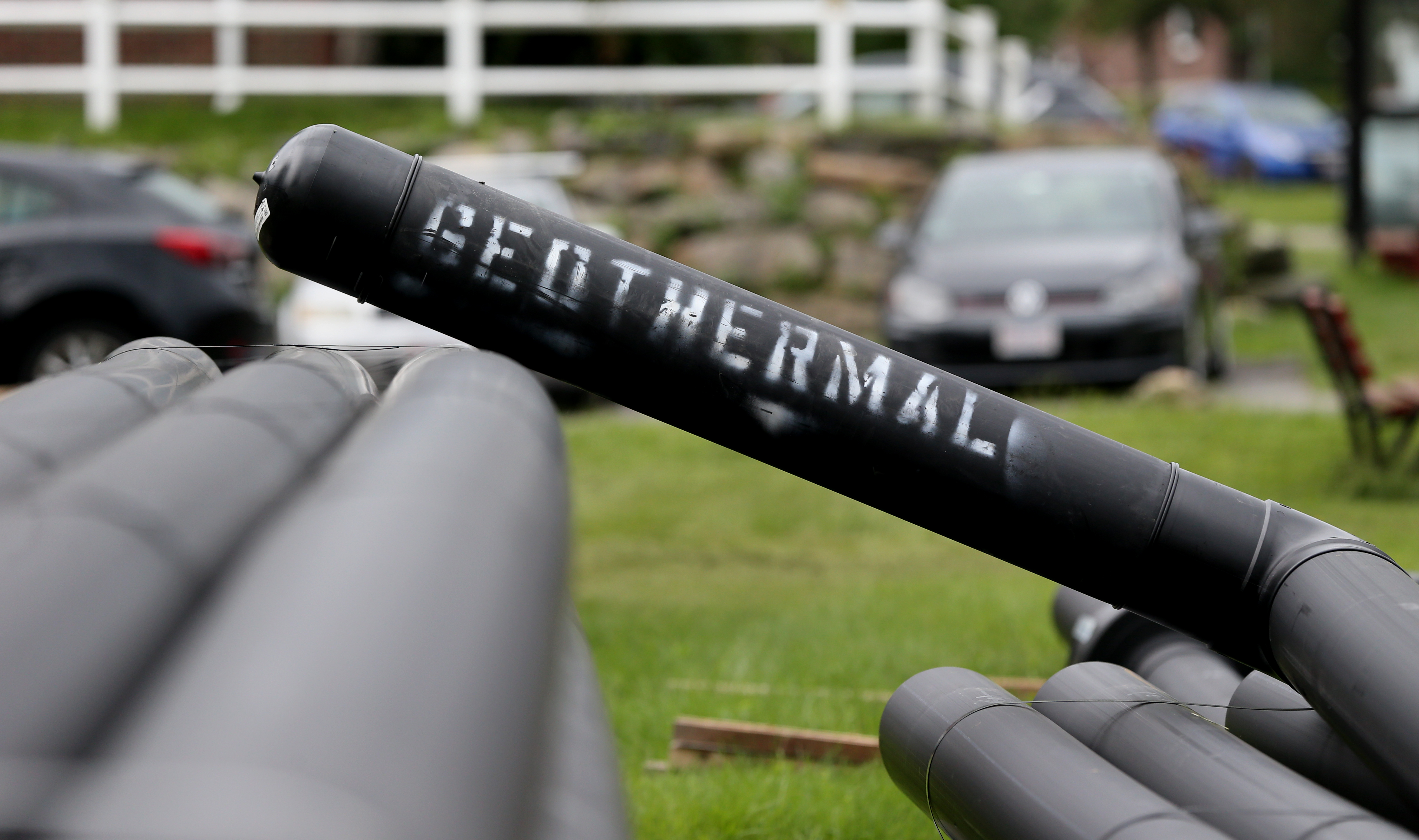 A pipe marked "geothermal" leans on other pipes in a residential neighborhood