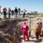 Contractors and attorneys for Chevron watch from above on April 10, 2024 as Hawk Dunlap, Daniel Charest and Sarah Stogner (from left) inspect an excavated well on April 10 at Antina Ranch in Crane County, Texas. Credit: Mitch Borden/Marfa Public Radio
