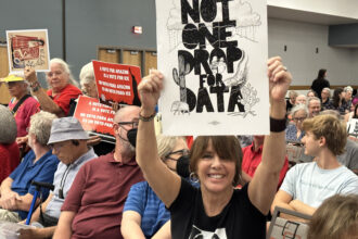 At the Tucson Convention Center in August 2025, demonstrators opposed "Project Blue," a massive data center installation proposed by Amazon Web Services. Data centers have also now become a flashpoint in Phoenix, the third largest data center market in the country. Across the state, ratepayers are linking data center development to higher electric bills. Credit: Wild Horizons/Universal Images Group via Getty Images