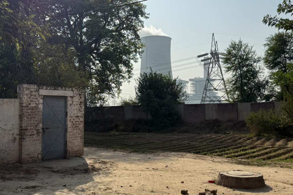 The cooling tower of the Chinese-financed Sahiwal coal plant just beyond the boundary wall of a colony. Credit: Aman Azhar/Inside Climate News