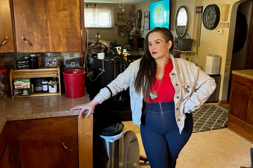 Candice DeSanzo is standing in her kitchen with a somber expression.