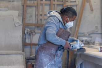 A stone countertop fabricator wears a mask to help protect against airborne particles which can contribute to silicosis at a shop on Oct. 31, 2023, in Sun Valley, Calif. Credit: Brian van der Brug/Los Angeles Times via Getty Images