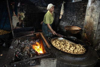 A worker fries tofu over a furnace fueled by a combination of plastic waste, wood and coconut husks at a tofu factory on May 22, 2025, in Sidoarjo, Indonesia. Credit: Robertus Pudyanto/Getty Images