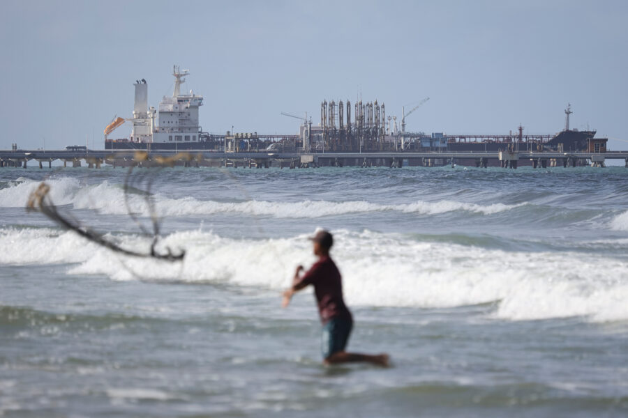 A fisherman casts a net into the sea as an oil tanker is seen anchored in the background on Dec. 18, 2025, in Puerto Cabello, Venezuela. Credit: Jesus Vargas/Getty Images