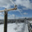 Utility lines with ice stretch over a snowy scene with a plowed road.