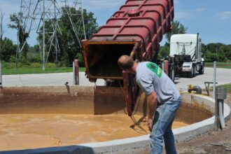 Farmer Ryan Rogers checks on a truck which has dumped food waste into a pit that feeds an anaerobic digester at Homestead Dairy in Plymouth, Indiana on July 13, 2015. The family-run farm invested in a biogas recovery system which transforms cow manure and other waste into enough electricity to power 1,000 homes. Credit: Mira Oberman /AFP via Getty Images