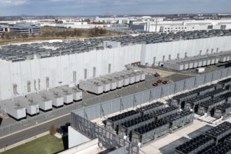 An aerial view shows cooling vent fans on the roof next to generators on the lower level of a Digital Realty data center in Ashburn, Virginia, in November 2025. Credit: Andrew Caballero-Reynolds/AFP via Getty Images
