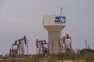 A water pipeline from the T-Bar Ranch terminates at this water tower on the western side of Midland, Texas, where oil pump jacks operate. Credit: Paul Ratje/Inside Climate News