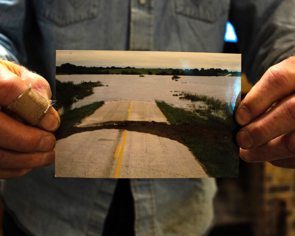 Blake Muir displays a photo of floodwater covering Highway 183 in October 1998. Credit: Dylan Baddour/Inside Climate News