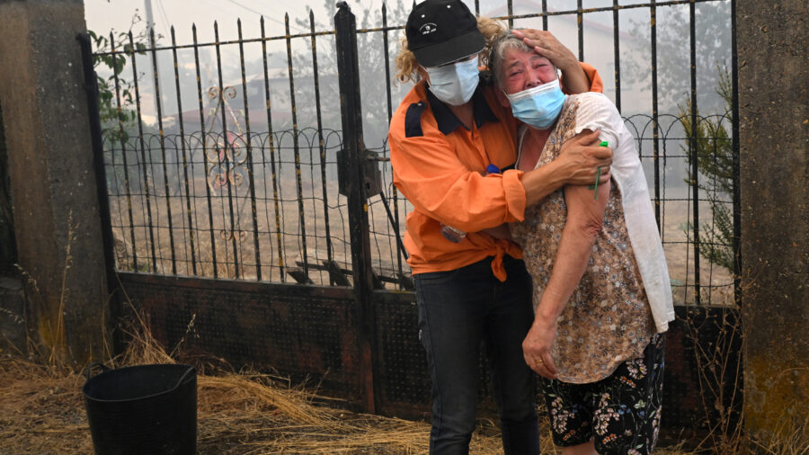 A Civil Protection member comforts a woman as a wildfire burns in the village of Veiga das Meas, Spain, on Aug. 16, 2025. Increasingly severe wildfire seasons around the world are one of the signs that some forests are at a climate threshold. Credit: Miguel Riopa/AFP via Getty Images