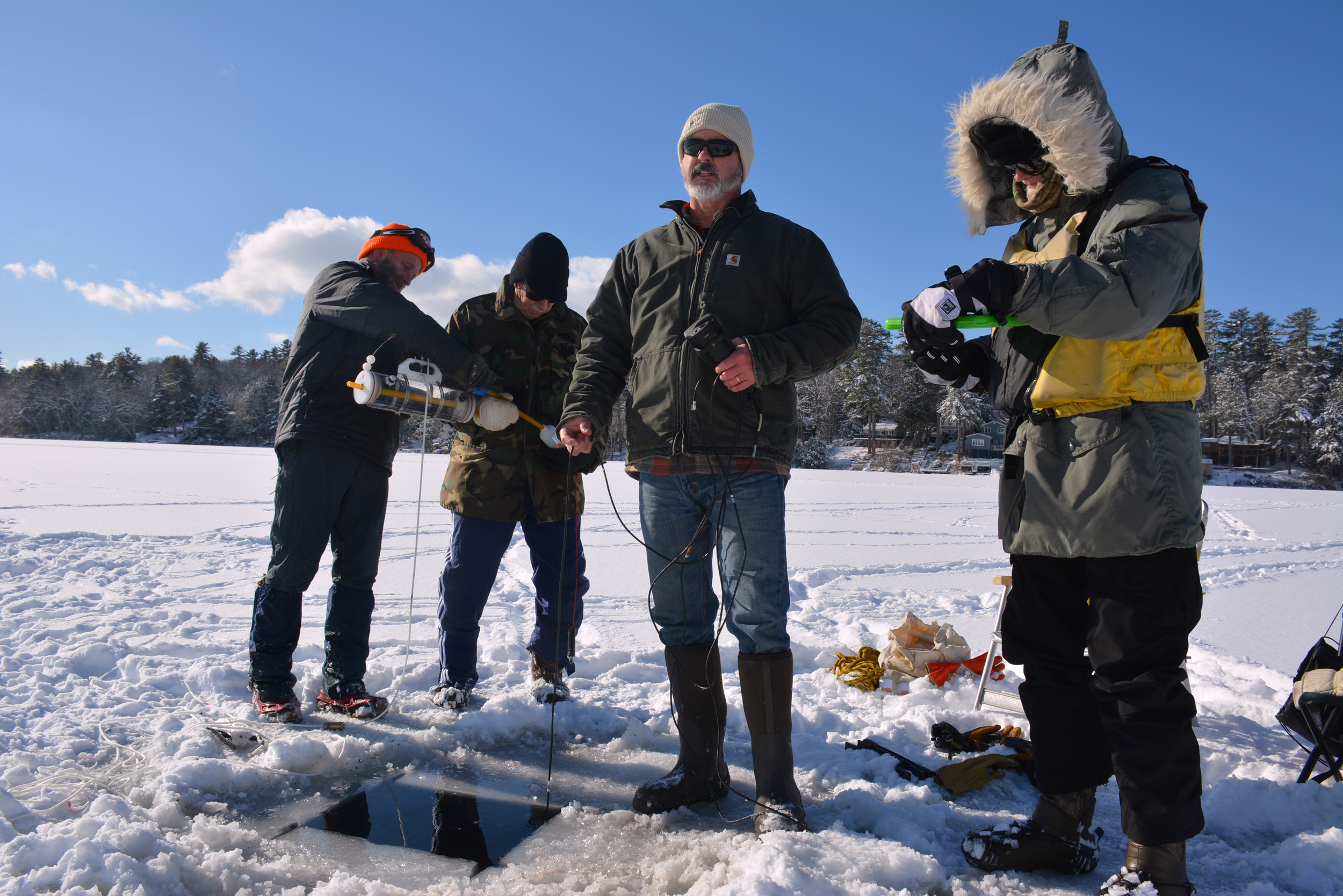 Lake Stewards of Maine members collect samples and measure water quality on Highland Lake in January 2026. As part of the Lake Stewards, the men track ice cover and year-round water quality of their home lake. Credit: Sydney Cromwell/Inside Climate News