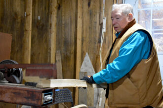 Richard Silliboy uses a machine to pound an ash log in his workshop. Once pounded, the log will divide into layers that can be separated and thinned into strips for basketmaking. Credit: Sydney Cromwell/Inside Climate News