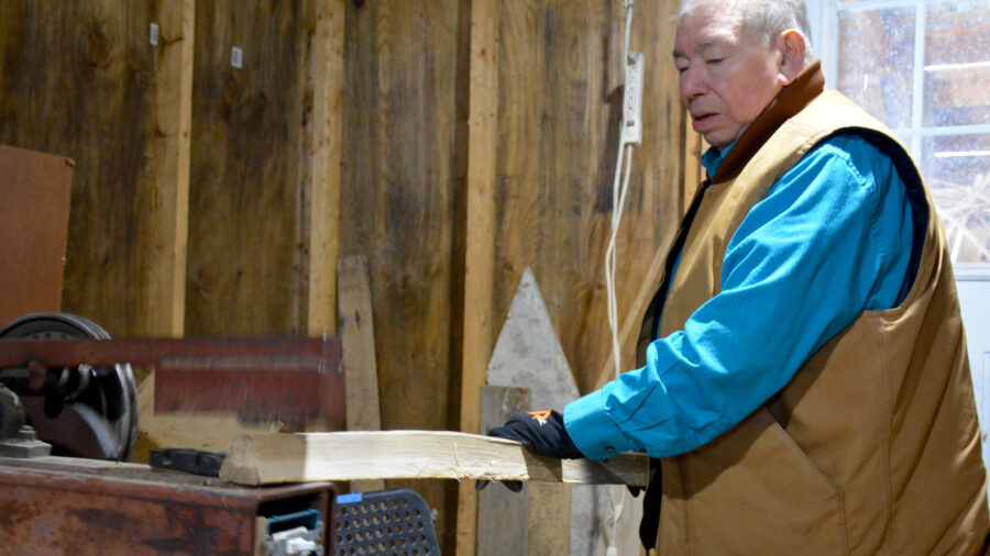 Richard Silliboy uses a machine to pound an ash log in his workshop. Once pounded, the log will divide into layers that can be separated and thinned into strips for basketmaking. Credit: Sydney Cromwell/Inside Climate News