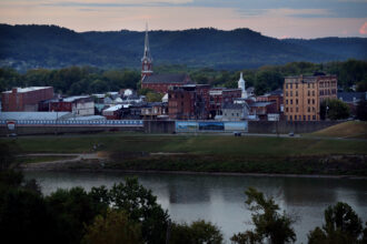 The view shows the river in the foreground, with the town and mountains behind.