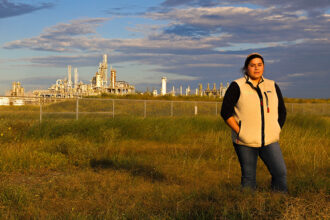 Elida Castillo, an environmental organizer from San Patricio County, stands outside Exxon’s plastics plant near her family home in 2022. Credit: Dylan Baddour/Inside Climate News